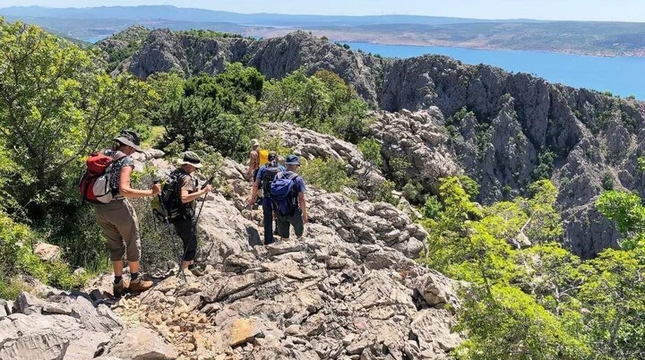Wandergruppe mit Meerblick | © DAV Markt Schwaben | Foto Hildegard Petschik Fünf Wandernde auf felsigem Pfad mit Blick auf das Meer und entfernte Berge unter blauem Himmel. | © DAV Markt Schwaben | Foto Hildegard Petschik