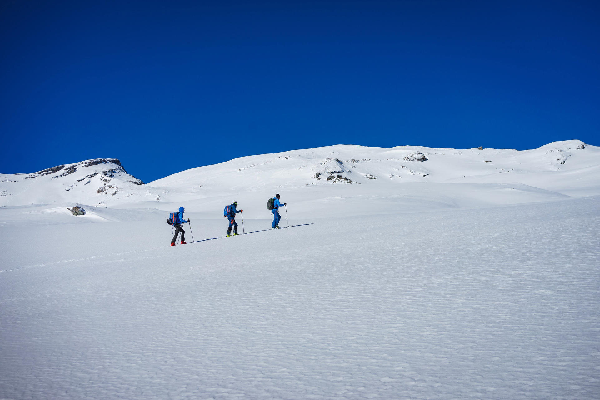 Drei Personen auf einer Skitour in einer schneebedeckten Landschaft unter klarem blauen Himmel. | © Markus Sellmeier 2022